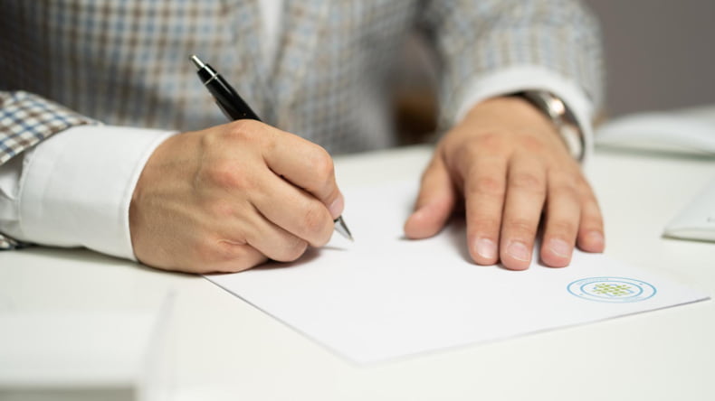Imagen de una persona firmando la compra de una casa en la que hay que pagar IVA