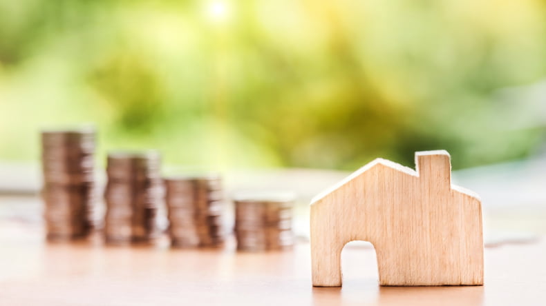 Imagen de dinero y una casa representando el precio del seguro del hogar en una vivienda de obra nueva