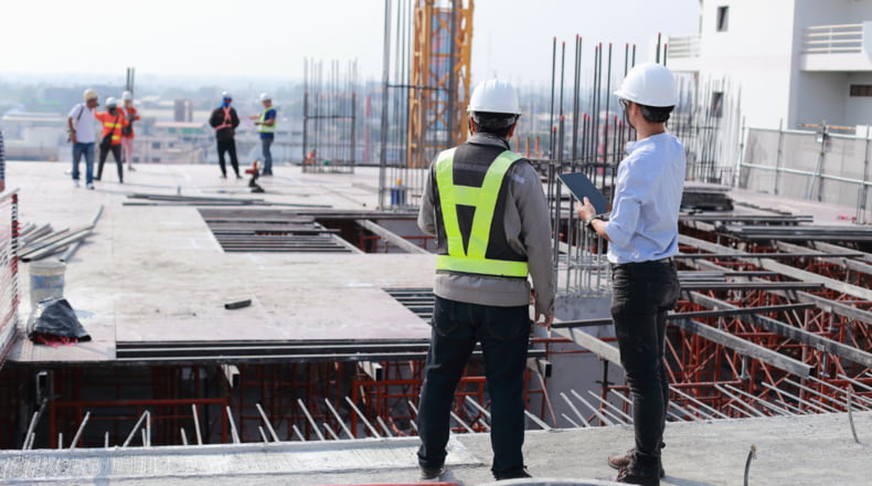 Ingenieros consultando planos en obra de construcción